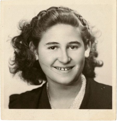 Black-and-white passport photograph of a young teenage woman smiling at the camera. She has wavy, dark brown, shoulder-length hair.