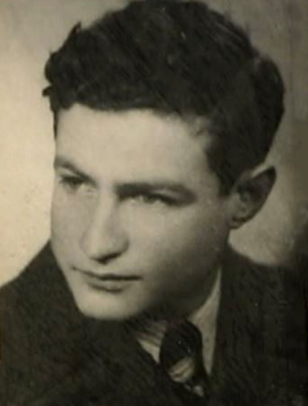 Black-and-white photograph of a young man's profile, looking towards the left of the camera. He wears a suit and has curly dark brown hair.