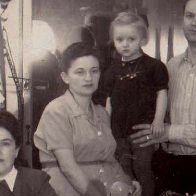 Black-and-white photograph of a young woman sitting with a young child behind her.