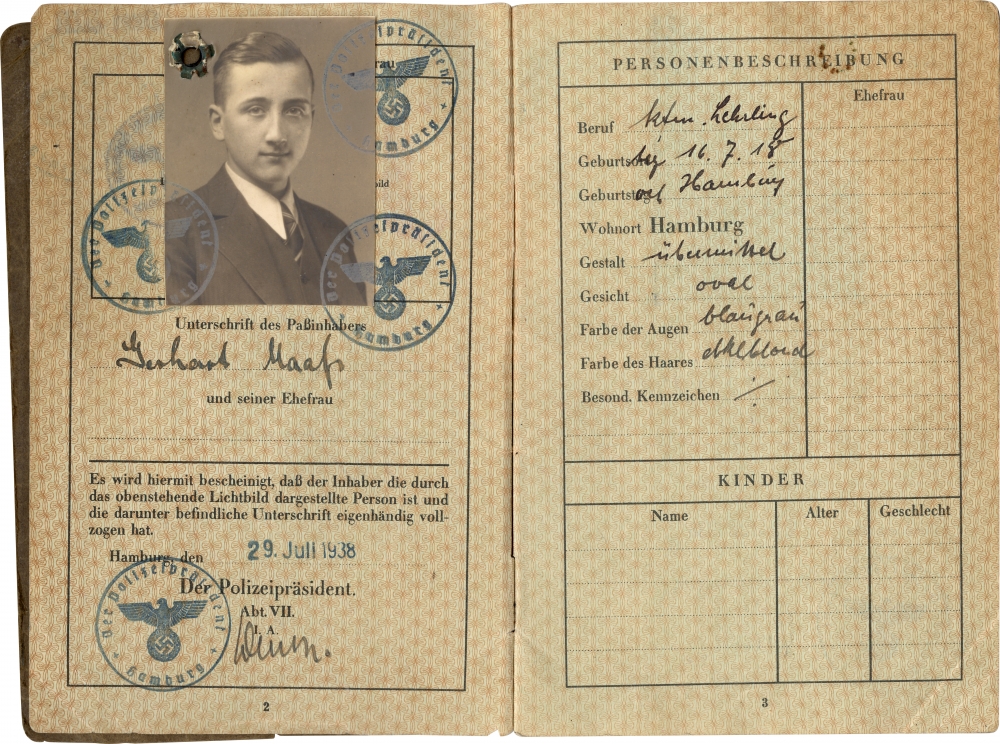 Two pages of a passport with blue stamps and black handwriting. The left page features a black-and-white identity photograph of a young man wearing a suit and tie.