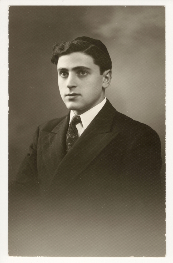 Black-and-white portrait photograph of a man in a suit and tie, looking towards the left of the camera. He wears a kippah on his head.