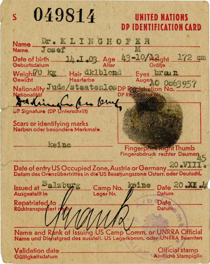 Copy of an aged yellow identity document. It contains red typed text with handwritten signatures, stamps, and a black fingerprint.