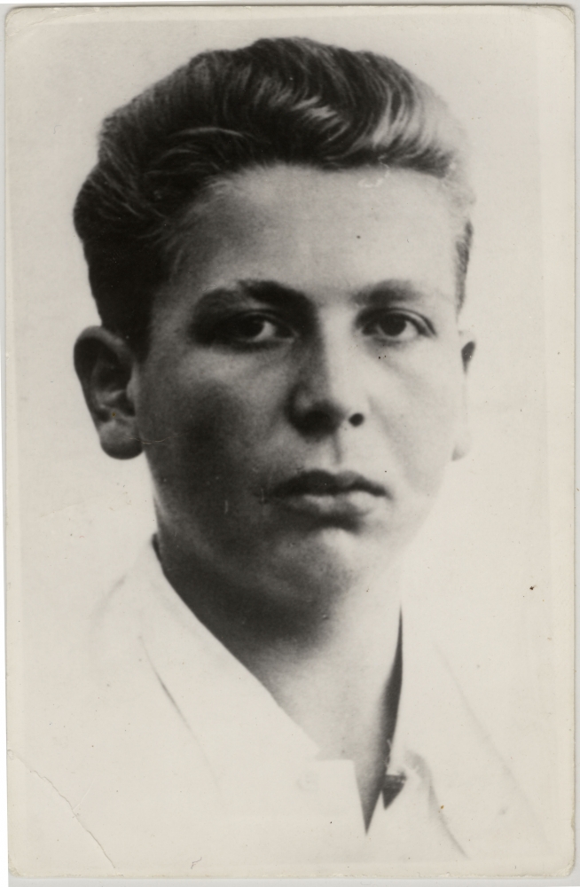 Black-and-white portrait photograph of a young man, approximately 15 years of age. The young man, wearing a white collar shirt with his hair brushed back, looks straight at the camera and does not smile.