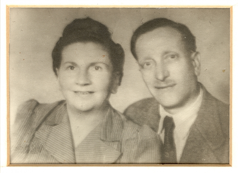 Black-and-white photograph of the bust of a man and woman smiling at the camera. The man wears a suit and tie, and the woman has her hair up.