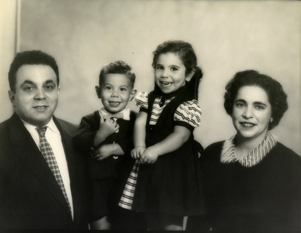 Black-and-white photograph of a man and woman with two young children, all smiling at the camera.