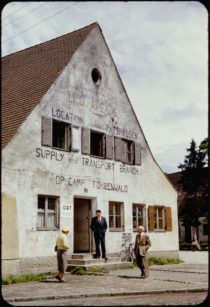 Diapositive en couleur d'une vue extérieure d'un bâtiment de trois étages. Trois hommes se tiennent devant le bâtiments.