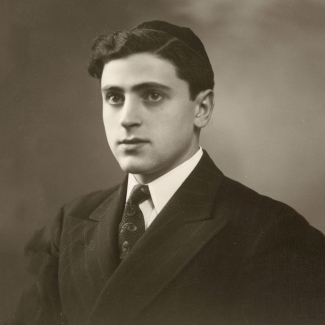 Black-and-white portrait photograph of a man in a suit and tie, looking towards the left of the camera. He wears a kippah on his head.