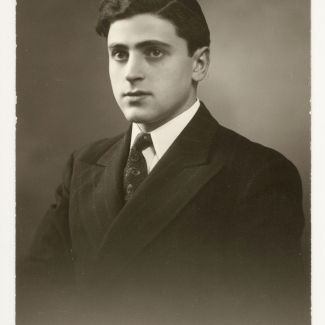 Black-and-white portrait photograph of a man in a suit and tie, looking towards the left of the camera. He wears a kippah on his head.