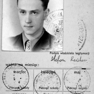 Black-and-white document with a photograph in top-left corner of a young man with combed-back hair, wearing a suit and tie. The document contains Polish writing, four stamps, and a signature.