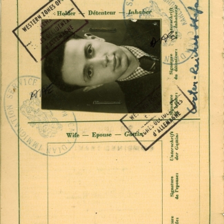 Beige-coloured page of an official document containing several stamps, signatures, and handwriting. One page includes a black-and-white portrait of a young man with combed-back hair and a suit and tie, positioned sideways on the top of the page.