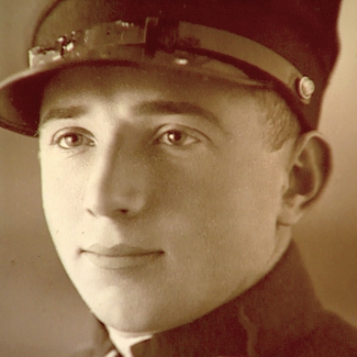 Photo de couleur sépia d'un gros plan du visage d'un homme. L'homme regarde à gauche de la caméra et porte ce qui semble être un uniforme militaire.