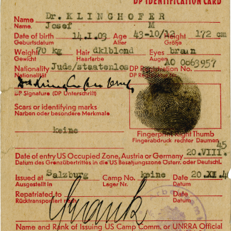 Copy of an aged yellow identity document. It contains red typed text with handwritten signatures, stamps, and a black fingerprint.