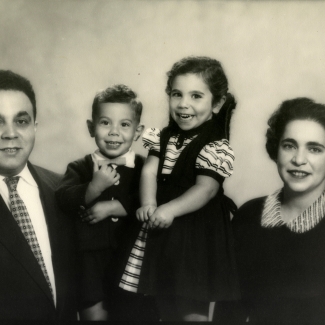 Black-and-white photograph of a man and woman with two young children, all smiling at the camera.