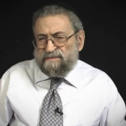 Screenshot of Holocaust survivor Joseph Lazar video testimony. He is sitting in front of a black background, and looking to the left of the camera. The camera shows his face and shoulders