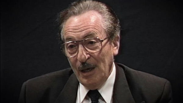 Screenshot of Holocaust survivor Michael Kutz video testimony. He is sitting in front of a black background, and looking to the left of the camera. The camera shows his face and shoulders.